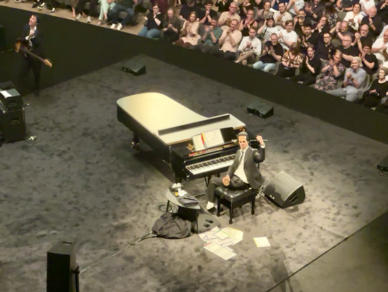 Nick Cave winkt, Colin Greenwood im Hintergrund