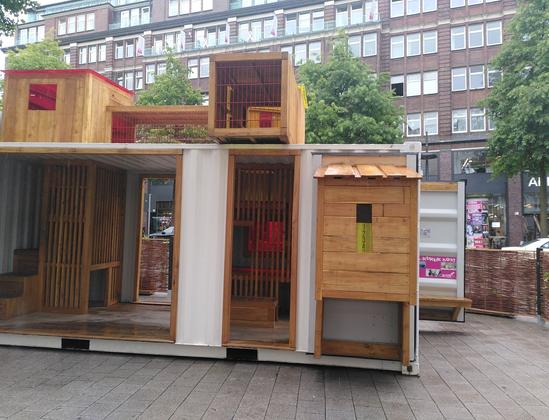 Side view of the container with stairs to the roof. There are some play elements on the roof protected with grating. More play elements in the container.