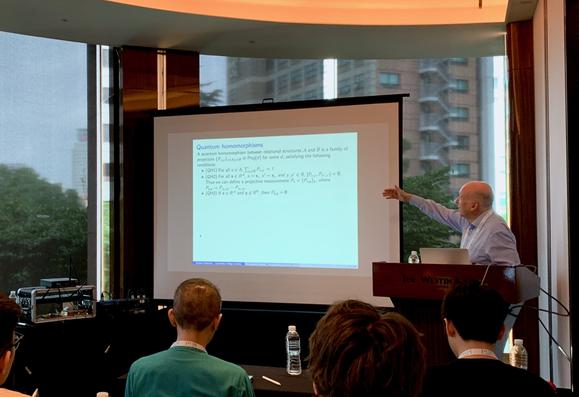 Samson Abramsky giving a talk, pointing to a slide about quantum homomorphisms.