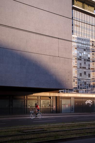 Bicyclist in front of a modernist facade, with a play of light and shadow in the evening sun.