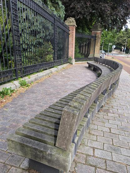 Wooden bench next to an old fashioned iron gate.