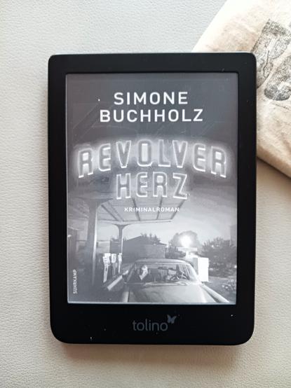 Foto eines E-Book-Readers mit dem Schwarz-Weiß-Cover des Buches, auf dem eine Tankstelle zu sehen ist, an der ein Auto steht. Auf dem Beifahrersitz eine Frau, der Fahrersitz ist leer.