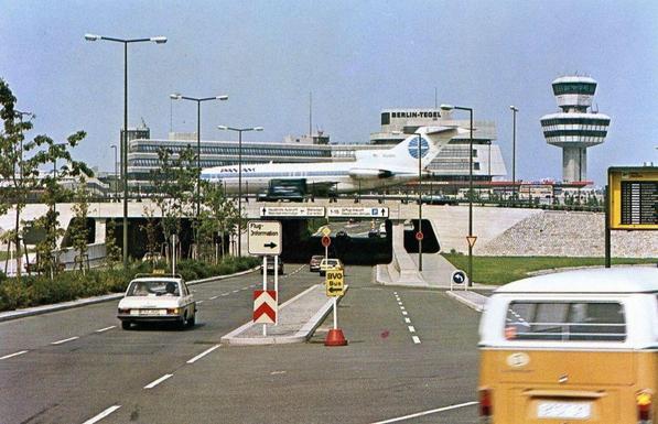 The view is from the road way as a 727 passes on a bridge above.