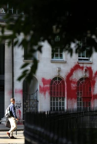 A white-walled building with arched windows covered in red paint.