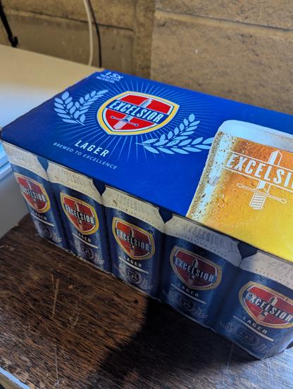 Pack of very very cheap larger, called Excelsior, on a wooden table.