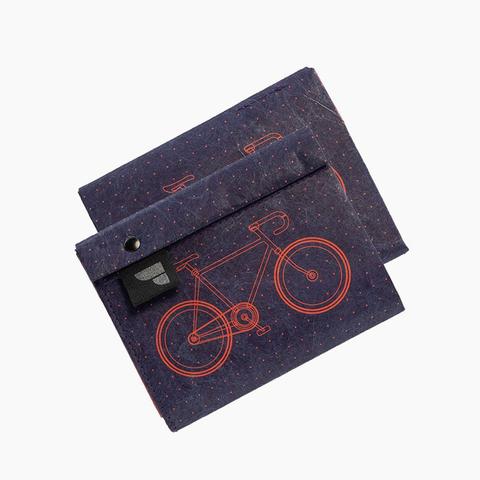 Blaues Portemonnaie mit Magnetverschluss. Es ist sehr flach und lässt sich aufklappen. Das Portemonnaie hat ein Fahrrad-Motiv