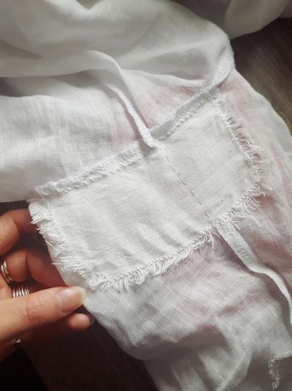 From the inside, a patch has been overcast onto the under the arm bit of the sleeve, going across the sleeve seam and attaching to the arm's eye seam. The patch is white linen, with very frayed, fluffy edges, the fabric secured just past the fluffy bit.