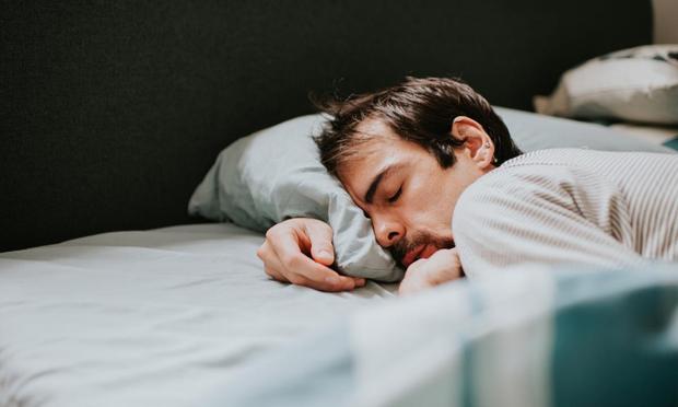 Un hombre durmiendo en una cama, acurrucado en una almohada suave. (Getty Images)