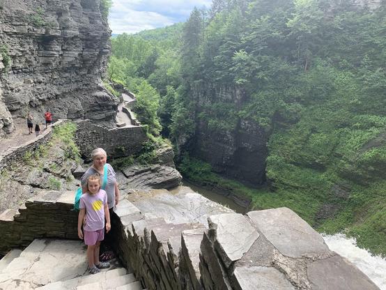 Two people standing next to waterfall at top of gorge