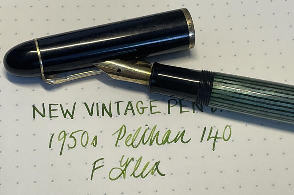 A vintage 1950s Pelikan 140 fountain pen is positioned above handwritten text on dotted paper, which reads “NEW VINTAGE PEN” and “F Flex” in green ink. The pen has a green/black striped body and a gold nib