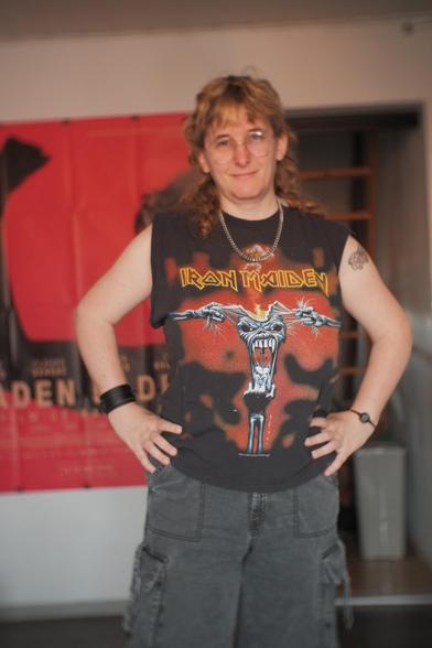 Autoportrait de moi, j'ai un pantalon noir à lanières, un t-shirt Iron Maiden dont j'ai décousu les manches, une chaîne en collier et un bracelet « de force » au poignet.