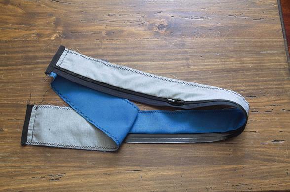 two long rectangles of fabric sewn in a loop: the outer is blue and the lining gray, and there is a water resistant zipper sandwitched in between. the seams are finished by binding them with tape.