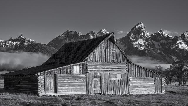 The Moulton Barn on Mormon Row in Grand Teton NP, Wyoming, processed in BW. Snow-capped Teton Mountains in the background.