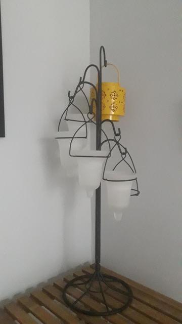 A candelabra made of transulcent white glass votives in an inverted bell shape, hanging from a black metal post in an elegant spiral. There's a random yellow candle holder in the top spot - ignore that.