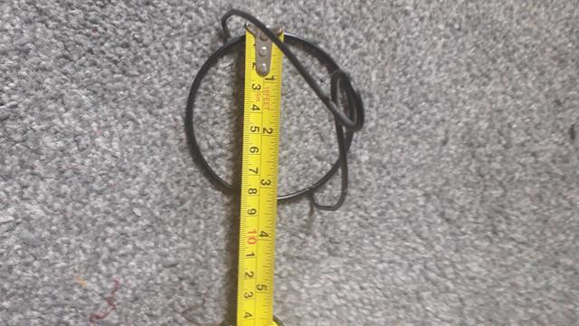One of the black wire habgers that support the votives, with a tape measure showing it is 3 and a quarter inches across.