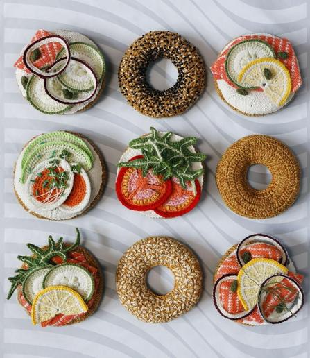 Photo of nine textile art creations made to look like bagels with various toppings such as egg and salmon