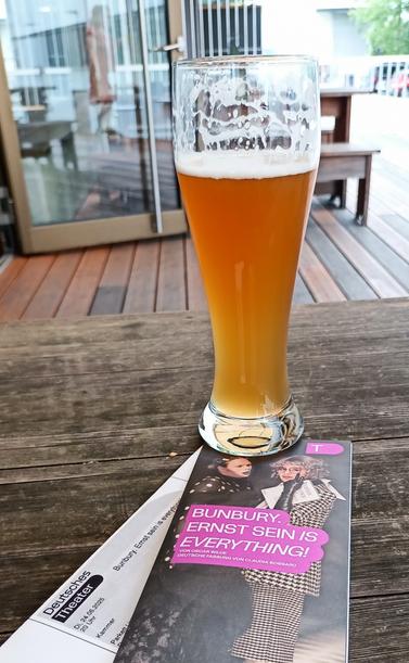 Das Ticket, das Programmheft und ein Glas alkoholfreies Hefeweizen