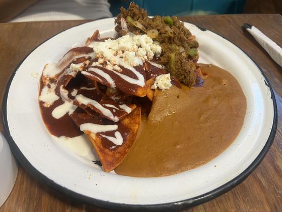 Chilaquiles con machaca y frijoles sobre plato blanco