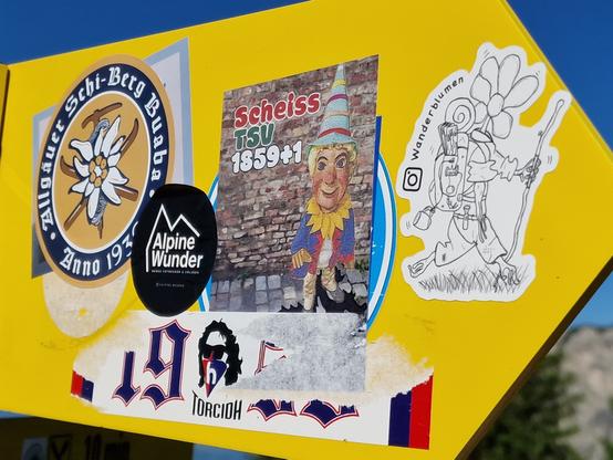 Wegweiser mit zahlreichen Aufklebern.