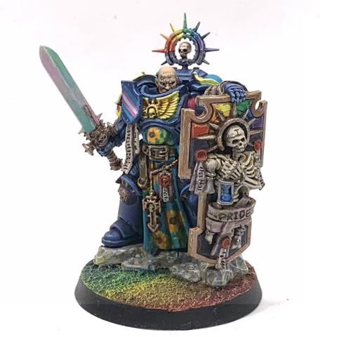Large warrior in dark blue armor with pansexual color (blue, yellow, and magenta) decorations. He carries a pearlescent sword and a large bulwark shield with rainbow colors behind a skeleton holding an hourglass and wrapped in scrolls that say "Pride". His tabard has sunflowers over light blue. He has a rainbow halo over his bear head, which stares out beyond the shield in defiance.