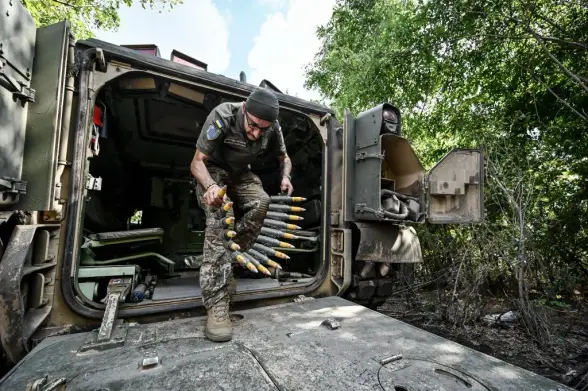 A Bradley IFV crew member of the 47th Mahura Mechanized Brigade carries a belt of munitions on the Zaporizhzhia front line, southeastern Ukraine