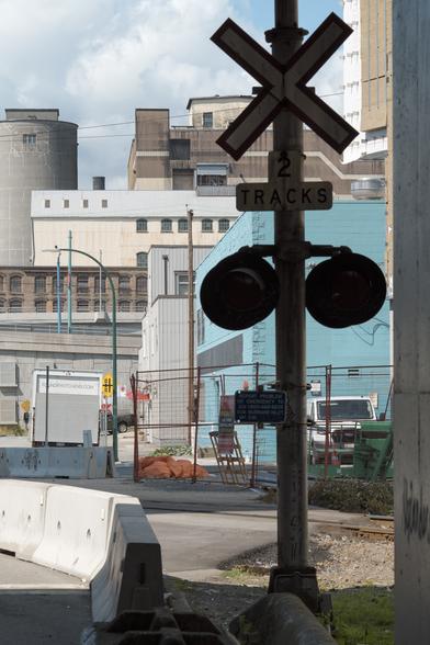 A stack of overlapping industrial buildings as viewed from a rail crossing.