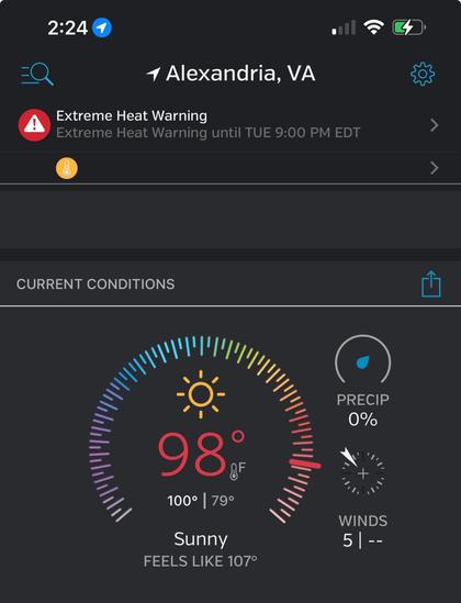 The image displays a weather app interface for Alexandria, VA, showing an extreme heat warning. The current temperature is 98°F, feeling like 107°F, with sunny conditions and no precipitation. Wind speed is 5 mph.