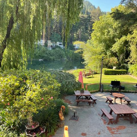 View from balcony on some picnic tables, a grassy area, and a nearby river.