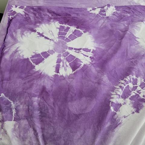 the top left corner of the flat sheet with the clearest and highest contrast patterns. the central and only whole circle features multiple pale concentric rings. the three inner rings are very thin, the outer ring is thicker