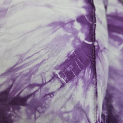 the edge of a pillowcase, focused on a small section of deep purple marked with a few very thin pale lines