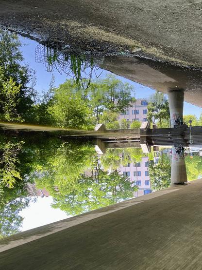 Pink Building and asphalt bridge reflected in water. The picture is turned upside down.