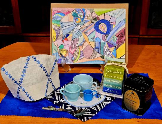 Tea tableau anchored by a vividly colored abstract art done with colored pencil. There are flashes of brilliant blue from the tea towel, tea cozy, a stacked candle, a mini cream pitcher, and in the artwork itself. The tea is Midsummer's Peach loose-leaf black tea by Harney and Sons.
