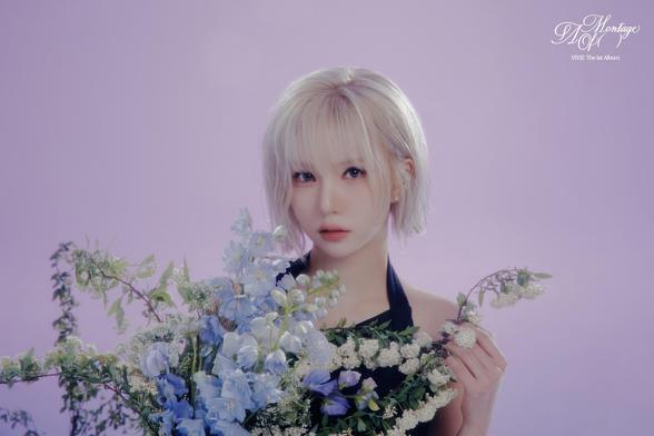 The image features the Kpop idol Eunha  with short, light-colored hair, holding a large bouquet of flowers against a soft purple background. The bouquet includes blue delphiniums, white flowers, and green foliage, creating a vibrant contrast with the purple backdrop. She is wearing a black halter-neck top, and the flowers are arranged in a way that they frame the person's upper body. The text "Montage ( )" and "VIVIZ The 1st Album" is visible in the top right corner, indicating the image's association with a music album. The overall composition is balanced, with the flowers and the person's attire complementing each other.

Provided by @altbot, edited by @jemmesedi