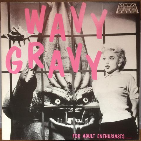 The image is an album cover featuring a striking and surreal design. The background is predominantly black and white, with a large, menacing creature resembling a monstrous plant or alien with multiple eyes and sharp teeth, behind a barred window. The creature's hand is raised, holding a small object. In the foreground, a woman with short, curly blonde hair, wearing a light-colored shirt and dark pants, stands to the right, looking surprised. The title "WAVY GRAVY" is prominently displayed in large, bold, pink letters across the center of the image. In the top right corner, there is a warning label that reads "BEWARE SCIENTIFIC EVIDENCE PROVES THAT PLANTS CAN READ OUR MINDS." At the bottom, the text "FOR ADULT ENTHUSIASTS..." is written in pink. The overall design is a mix of horror and humor, with a vintage aesthetic.

Provided by @altbot, generated privately and locally using Ovis2-8B
