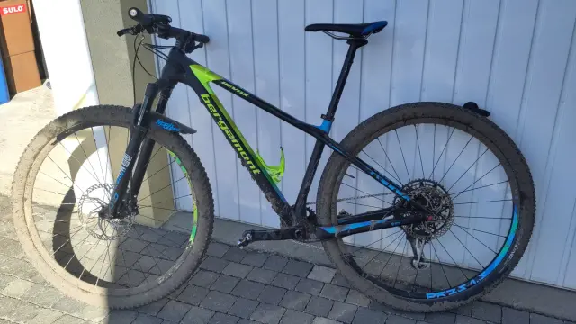 Ein schlammverkrustetes MTB lehnt an einer Garage.
