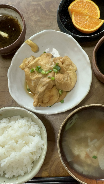 It’s simmered pouches made with deep fried tofu, aburaage. It’s sprinkled with chopped green onions. It’s put with Japanese mustard on the edge of dish. It’s served on the white uneven dish I made.