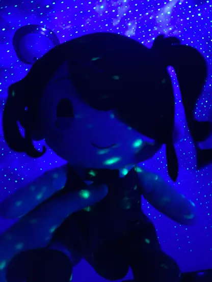 Me holding my Ame plush with a starry purple reflection on the wall.