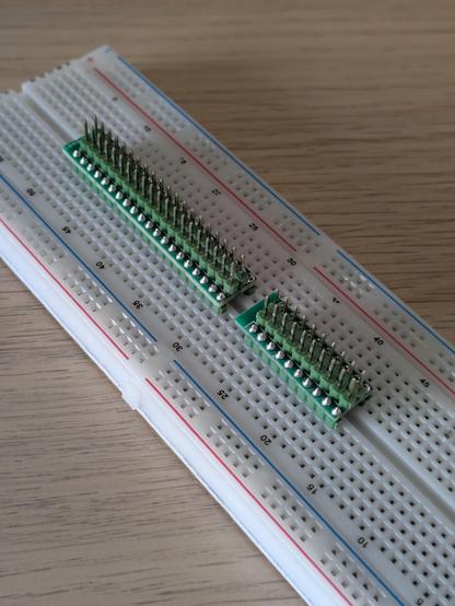 A photo of the two circuit boards plugged into a breadboard. They are intended to have a cable or device plugged into the top, and then have the individual pins from that cable broken out into the rows on a breadboard.