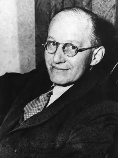 Ernest Walton in a suit, tie and glasses.