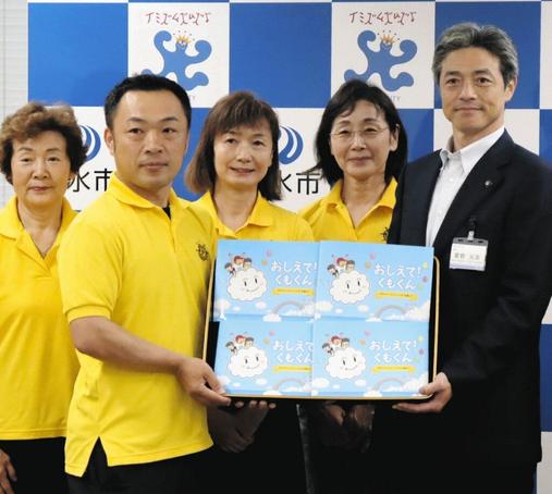 夏野元志市長（右）に絵本を渡す小柳勇人会長（左から２人目）＝射水市役所で