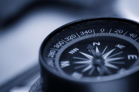Das Bild zeigt einen Kompass, der symbolisch für die Orientierung im Kostenmonitoring und zu Fördermitteln sowie die zielgerichtete Steuerung steht, indem er den Weg zu finanzieller Stabilität und effizientem Ressourceneinsatz weist. 
Im Zentrum des Bildes ist ein Kompass, dessen Nadel Richtung Nord zeigt. Der Kompass ist mit detaillierten Markierungen versehen, die die Grade anzeigen. Der Hintergrund ist blau und unscharf, was den Fokus auf die Kompassnadel verstärkt und die Idee der Richtung und Orientierung in finanziellen Angelegenheiten unterstreicht.
