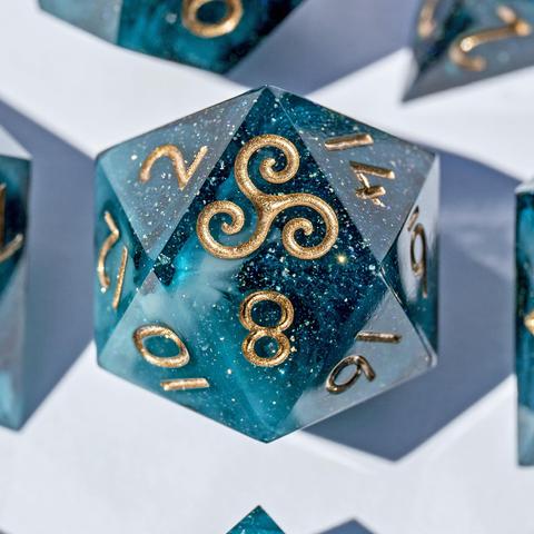 Detailaufnahme vom D20 in tiefem Petrol und Nummern in Goldbronze. Bei diesem D20 zeigt die höchste Seite eine Triskele statt der 20.