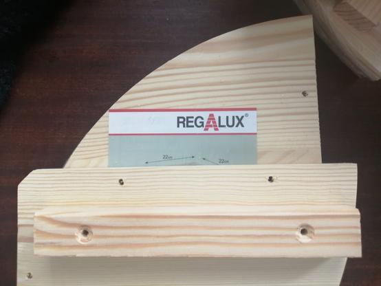 Photograph of a semi-circular wooden shelf with a wooden support cross bar. The screw holes on the cross bar do not line up with the screw holes on the shelf.