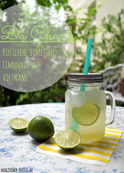 Weiße Tischplatte mit blauen Rosen. Darauf ein Glas mit Henkel und silbernem Deckel. Heraus ragt ein türkiser Strohhalm. Im Glas Eiswürfel, Limettenscheibe und Limettenlimonade. Das Glas steht auf einem gelb-weiß gestreiften Papier. Daneben liegt eine ganze und 2 Limettenhälften. Im Hintergrund grüne Pflanzen, helle Hauswand, eine unscharfe, weiße Gartenbank.