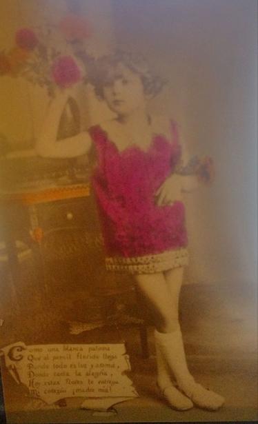 Fotografía en blanco y negro de una niña con un vestido rosa, sosteniendo flores, con texto poético en la parte inferior, resaltando un sentimiento de amor y nostalgia.