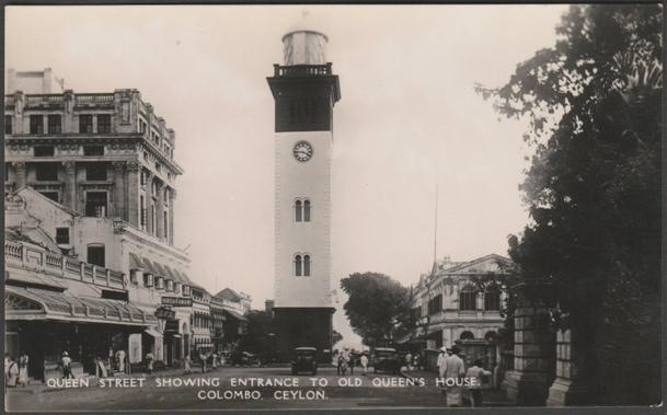 Monochrome real photographic postcard showing a view of Queen's Street in Colombo, Ceylon, and with the entrance to Queen's House.

Published by Plâté Ltd, Ceylon, No 5, c.1930s.

Postally unused.

Very good condition, with very slight corner bumps.