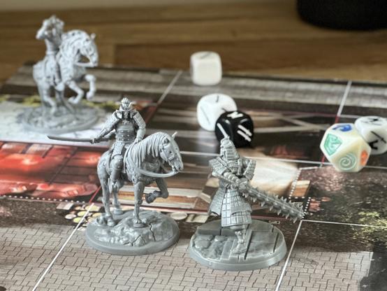 A mounted demon samurai squares off against a towering Crab clan champion with Tetsubo in this miniature board game
