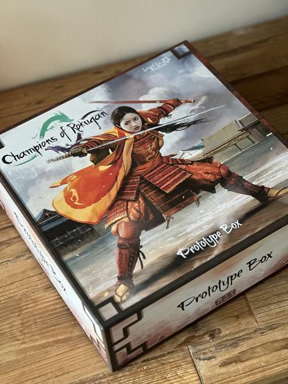 A resplendent Phoenix clan samurai takes a combat stance on the cover of the prototype box for Champions of Rokugan