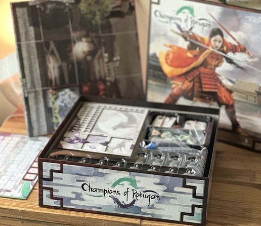 Open box shows a stack of components cards, and dice