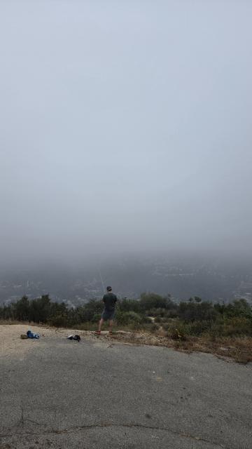 A person with a handheld radio looks out over fog